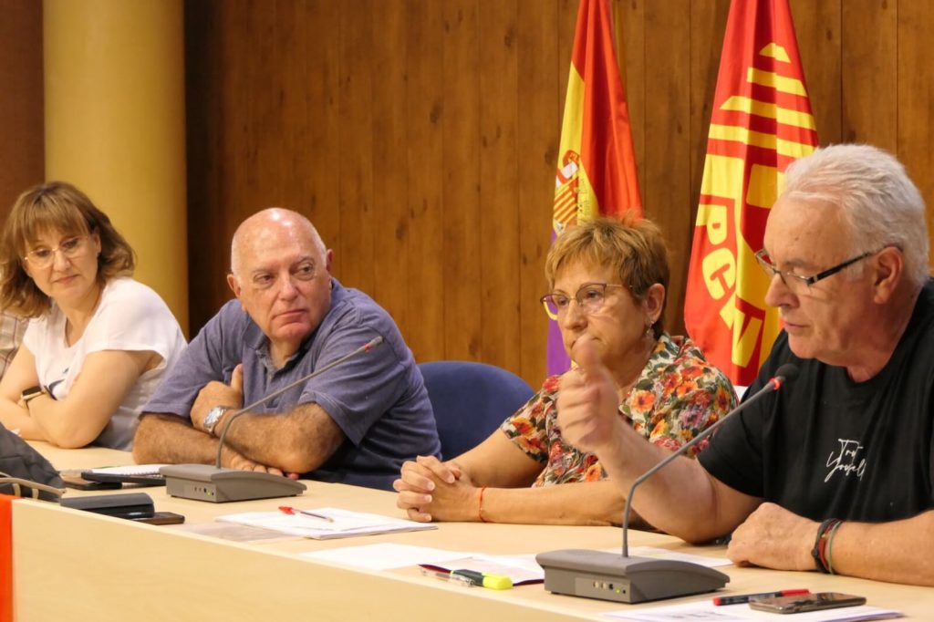 ponentes sentados a la mesa, interviene cayo lara al micrófono